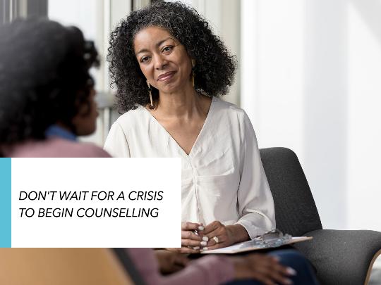 Graphic of two Black women with dark curly hair (one with back to camera) talking in a counselling context. Black upper case text in white text box with turquoise trim reads: 'Don't wait for a crisis to begin counselling'.