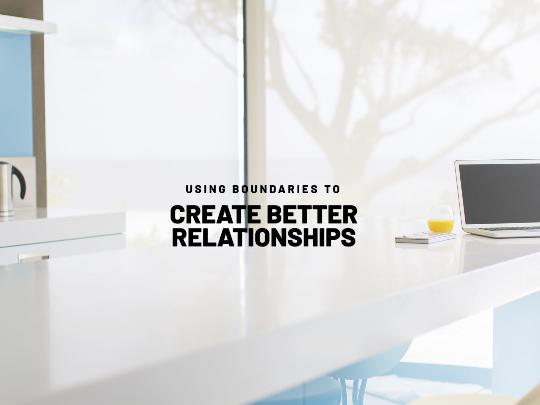 Image of white desk with laptop on far right hand side, and kettle seen on far left by window. Black upper case text in centre of image reads: 'Using boundaries to create better relationships'.