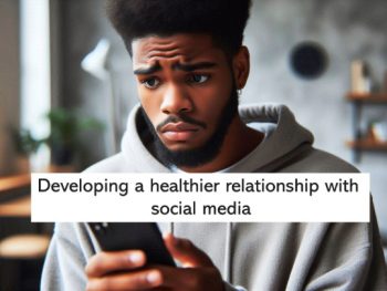 Young Black man with grey hoodie holding smart phone looking concerned with furrowed brow.